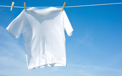 A plain white T-shirt hanging on a clothesline on a sunny day