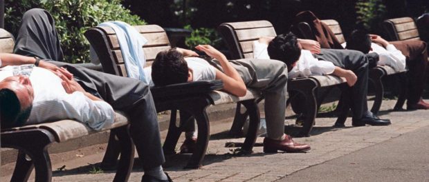 Japanese businessmen take naps on benches in Hibiy