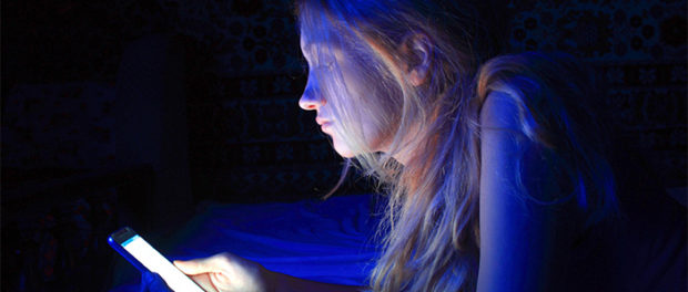 young woman using the smart phone on bed before sleep